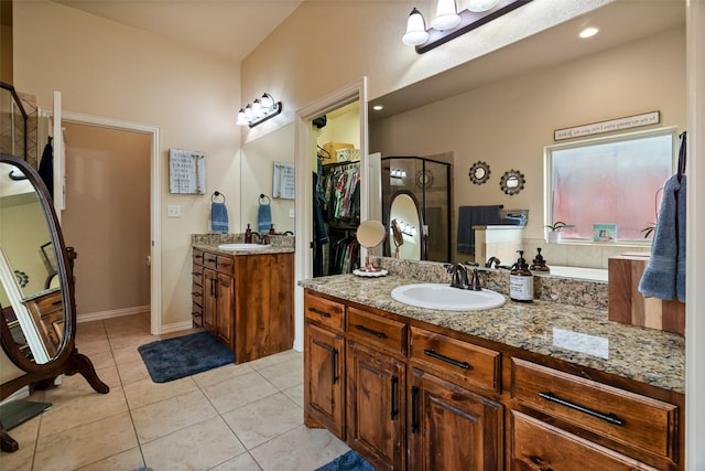 bathroom with a stall shower, tile patterned flooring, two vanities, and a sink