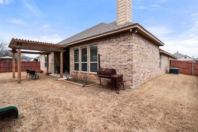 rear view of house featuring central AC unit, a fenced backyard, a chimney, a pergola, and brick siding