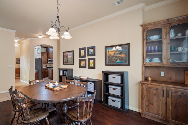 dining room featuring dark wood-style floors, arched walkways, visible vents, and crown molding