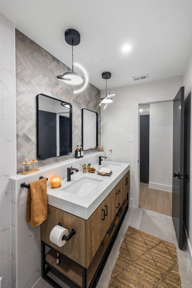 bathroom with double vanity, visible vents, and a sink