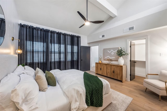 bedroom featuring visible vents, light wood-style flooring, a walk in closet, and beamed ceiling