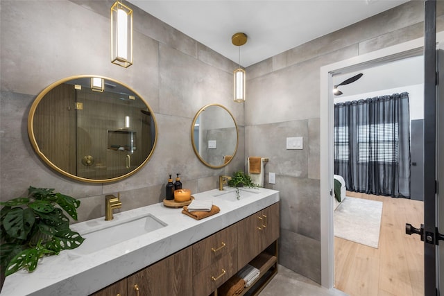 bathroom with tile walls, wood finished floors, double vanity, and a sink