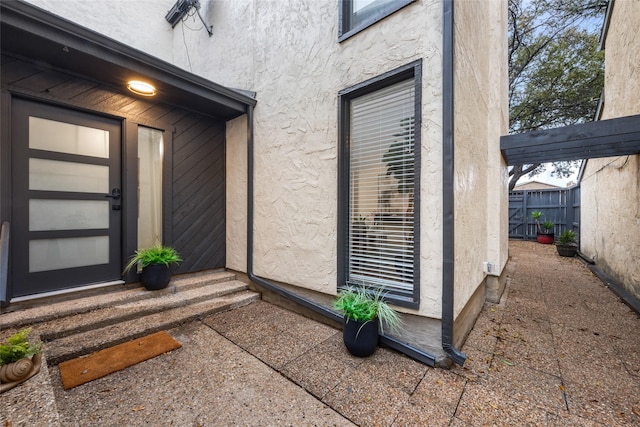 property entrance featuring stucco siding and fence