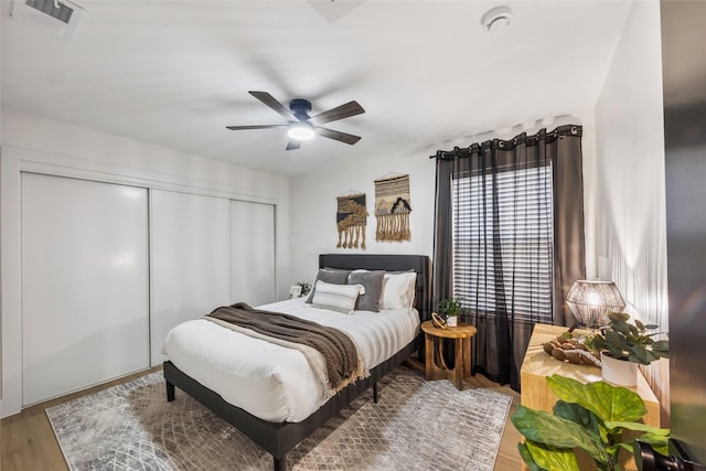 bedroom with visible vents, a closet, wood finished floors, and a ceiling fan