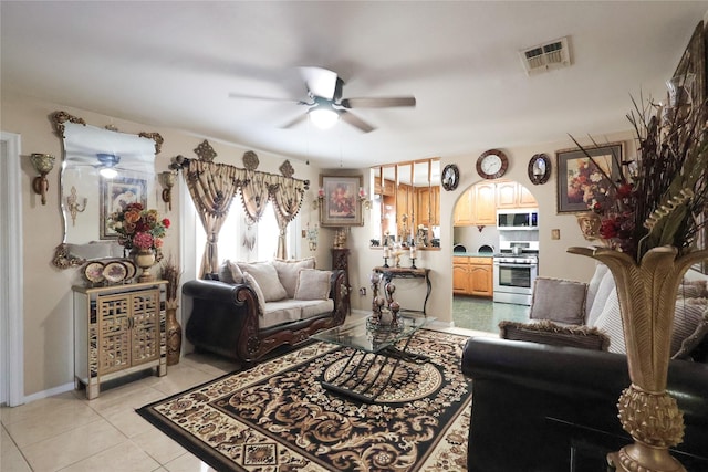 living area featuring light tile patterned floors, visible vents, arched walkways, and a ceiling fan