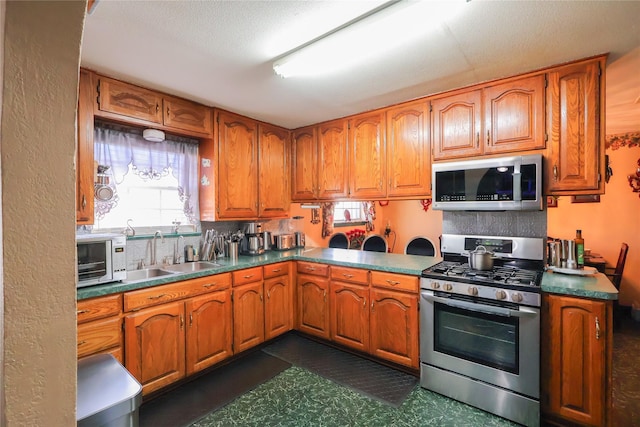 kitchen with stainless steel appliances, brown cabinetry, and a sink