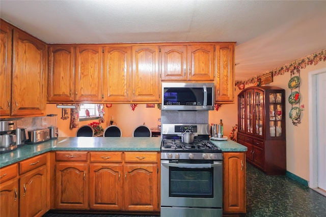 kitchen featuring stainless steel appliances, brown cabinetry, and baseboards