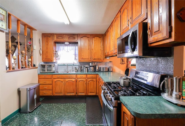 kitchen featuring stainless steel appliances, decorative backsplash, a sink, and brown cabinets