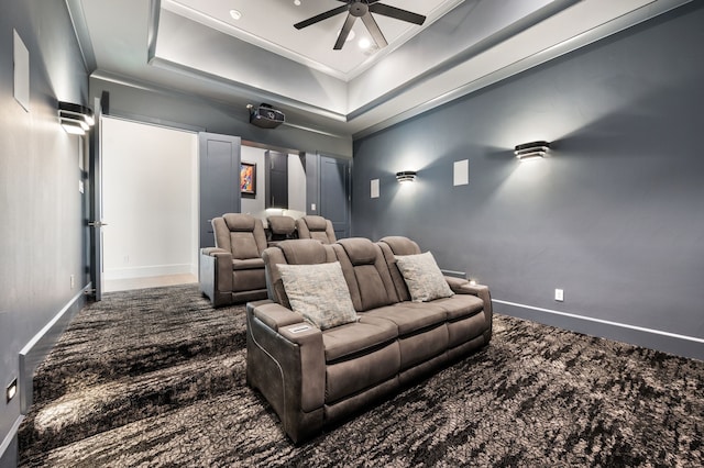 home theater with baseboards, ceiling fan, dark carpet, and crown molding