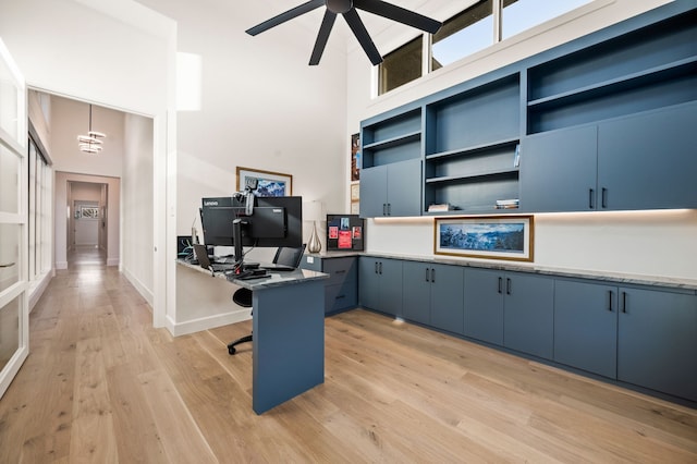 office with baseboards, a high ceiling, a ceiling fan, and light wood finished floors