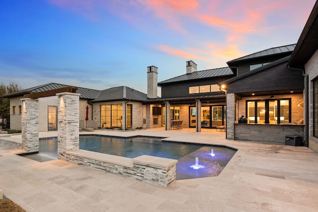 pool at dusk featuring an outdoor pool and a patio