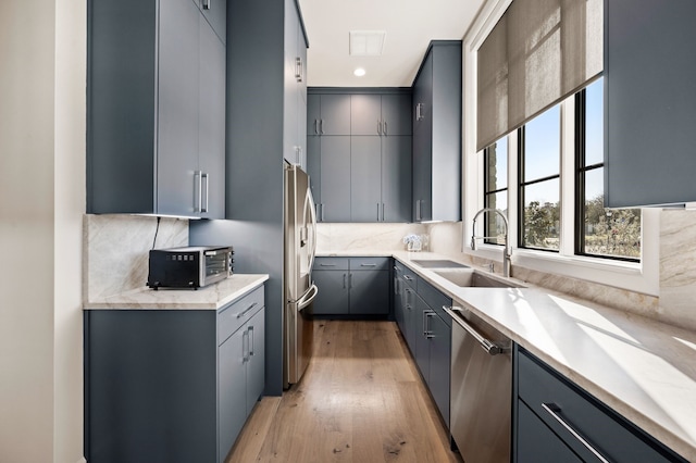 kitchen featuring gray cabinetry, a sink, tasteful backsplash, stainless steel appliances, and a toaster