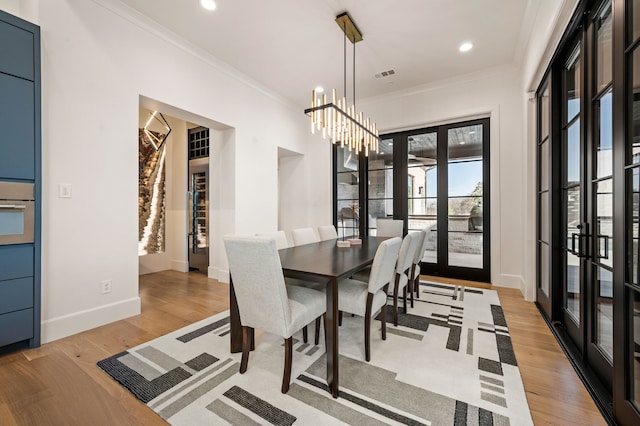 dining space featuring light wood finished floors, visible vents, crown molding, and baseboards