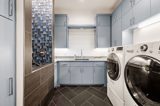 clothes washing area featuring cabinet space, dark tile patterned flooring, washing machine and dryer, and a sink