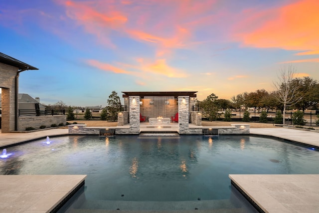 pool at dusk with exterior fireplace, a fenced in pool, a patio, and fence