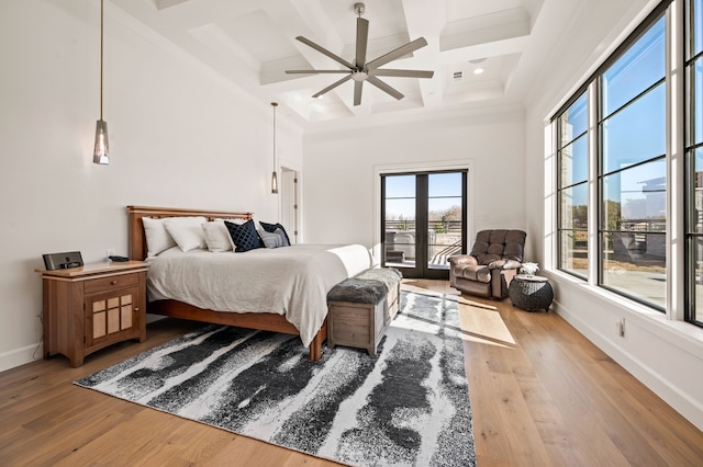 bedroom featuring baseboards, coffered ceiling, light wood-style flooring, a towering ceiling, and beamed ceiling