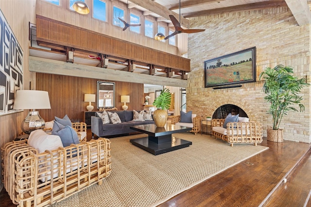 living room featuring a high ceiling, beamed ceiling, wood finished floors, and wood walls