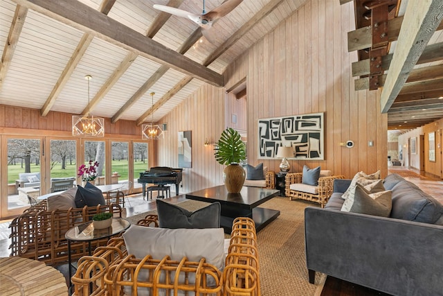 living area with high vaulted ceiling, beamed ceiling, wooden walls, and ceiling fan with notable chandelier