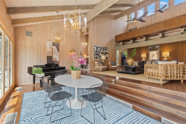 dining room featuring beamed ceiling, wooden walls, and wood finished floors