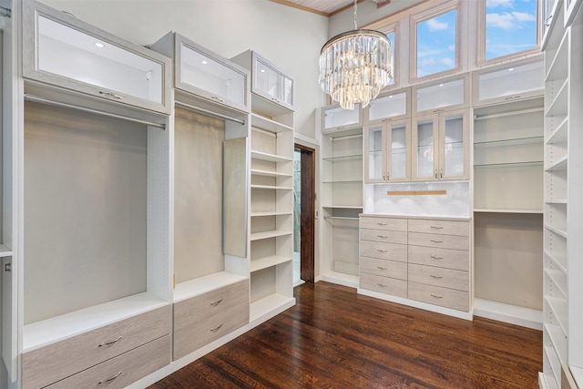 walk in closet with a notable chandelier and dark wood finished floors