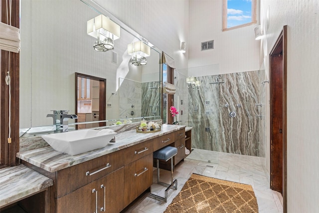 bathroom featuring a high ceiling, visible vents, vanity, marble finish floor, and a marble finish shower