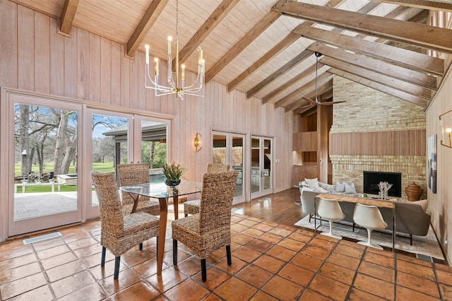 dining area with high vaulted ceiling, a notable chandelier, wood walls, french doors, and beamed ceiling