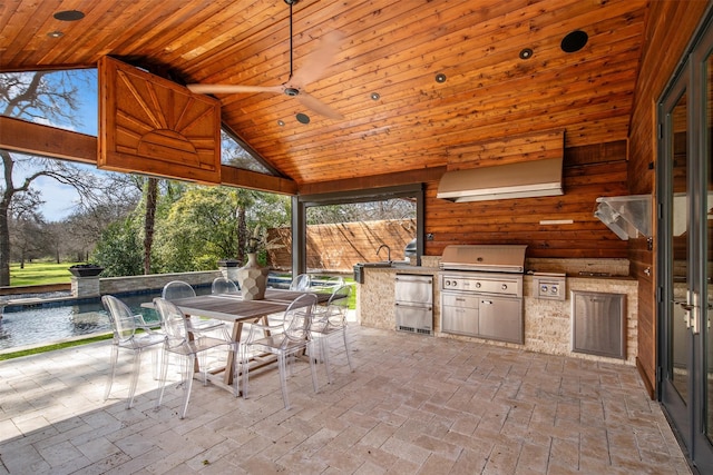 view of patio featuring outdoor dining space, a grill, a sink, fence, and exterior kitchen