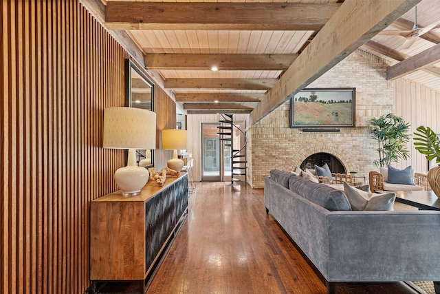 living area featuring a brick fireplace, stairs, hardwood / wood-style floors, and beamed ceiling