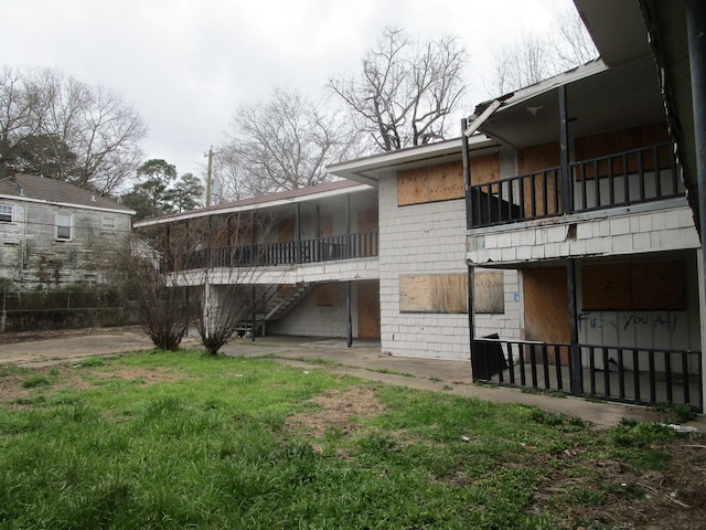 rear view of property featuring a sunroom, a balcony, and stairs