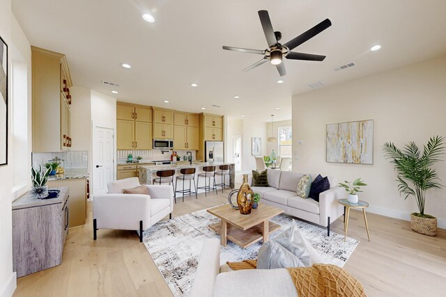 living room featuring visible vents, light wood-style floors, and a ceiling fan
