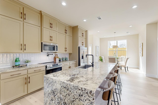 kitchen featuring a sink, visible vents, stainless steel appliances, and cream cabinetry