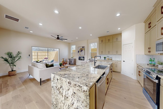 kitchen with a sink, appliances with stainless steel finishes, decorative backsplash, visible vents, and ceiling fan