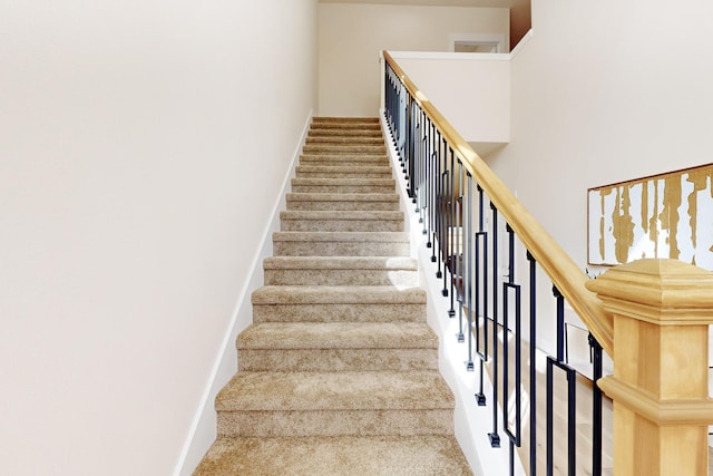 staircase with a towering ceiling and baseboards