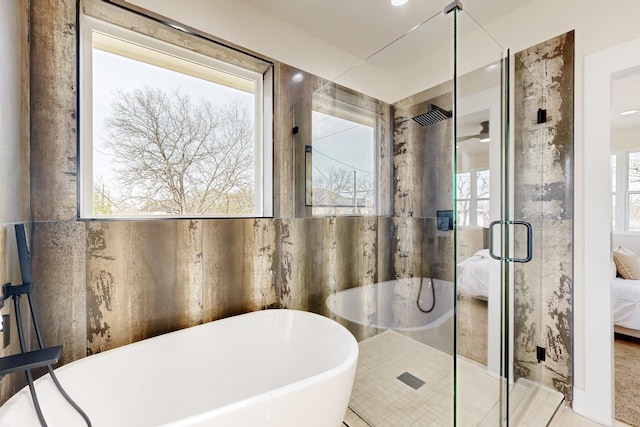 ensuite bathroom featuring tile walls, connected bathroom, a stall shower, and a freestanding bath
