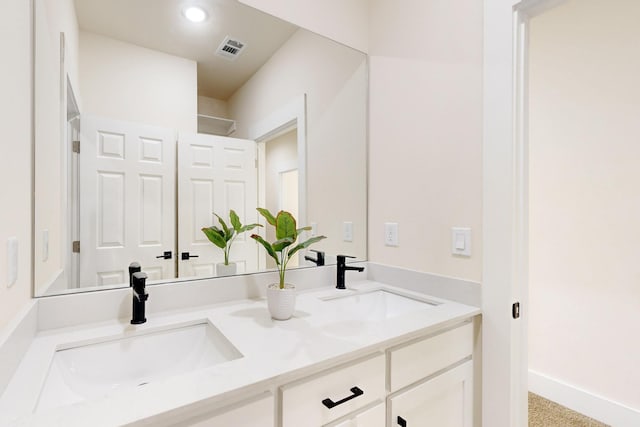 bathroom with visible vents, a sink, baseboards, and double vanity