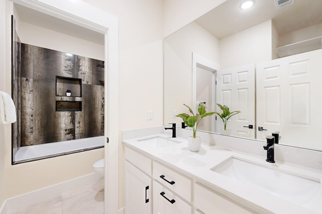 full bathroom with double vanity, tile patterned flooring, a sink, and toilet