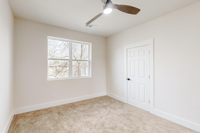 carpeted spare room with baseboards, visible vents, and a ceiling fan