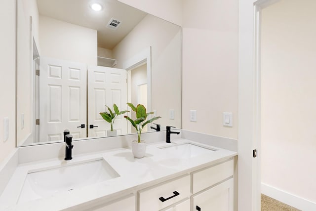 full bath featuring double vanity, a sink, baseboards, and visible vents