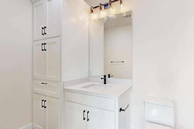 bathroom featuring toilet, vanity, and visible vents