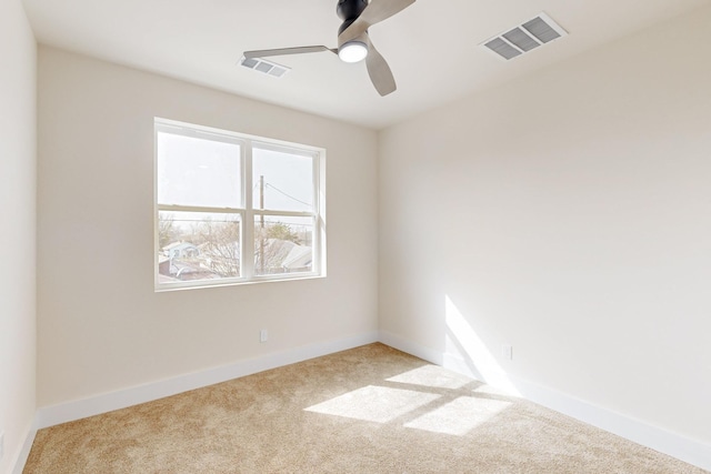 empty room with carpet floors, baseboards, visible vents, and ceiling fan