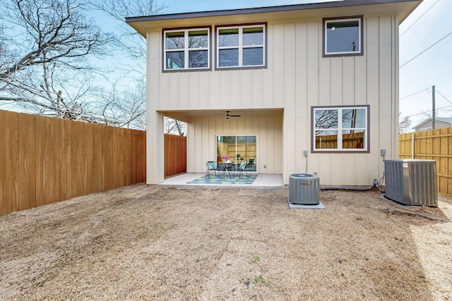 back of house with central AC, board and batten siding, a patio area, and a fenced backyard