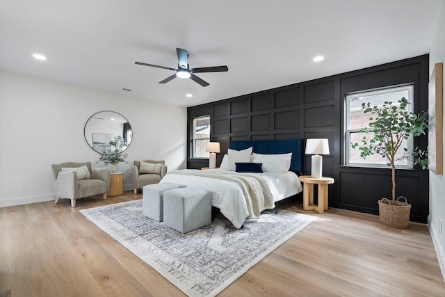 bedroom featuring light wood-type flooring, a decorative wall, and recessed lighting