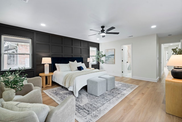 bedroom featuring recessed lighting, a decorative wall, visible vents, baseboards, and light wood finished floors