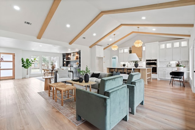 living area featuring high vaulted ceiling, light wood-style flooring, visible vents, and beam ceiling