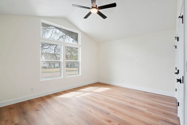 interior space featuring ceiling fan, light wood-style flooring, baseboards, and vaulted ceiling