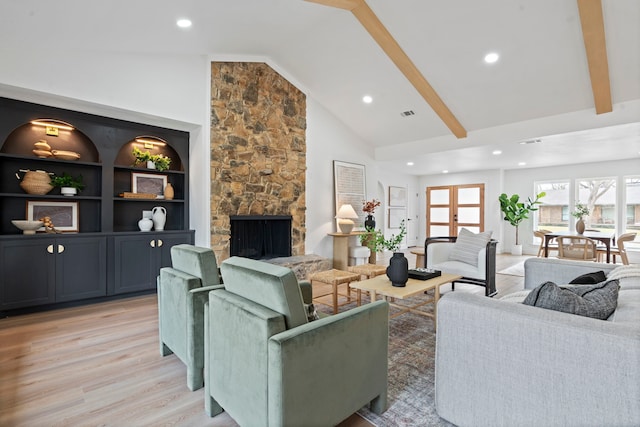 living room featuring light wood finished floors, a fireplace, high vaulted ceiling, and beam ceiling