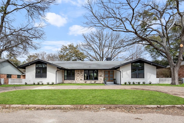 mid-century modern home featuring brick siding, a chimney, dirt driveway, a front yard, and fence