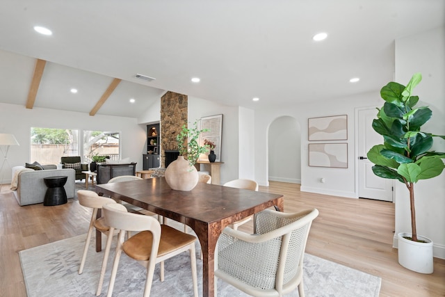 dining area featuring lofted ceiling with beams, light wood-style floors, visible vents, and arched walkways