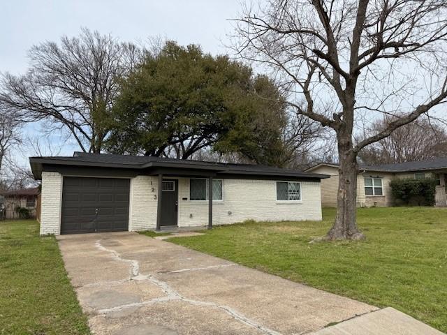 single story home featuring a front yard, brick siding, driveway, and an attached garage