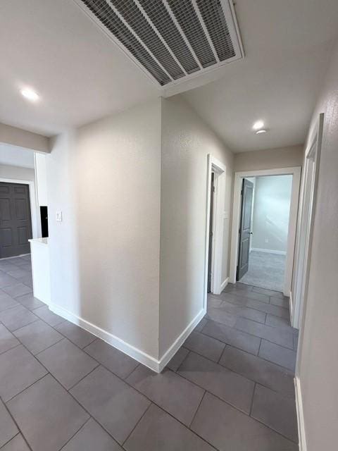 hall with visible vents, baseboards, and tile patterned floors